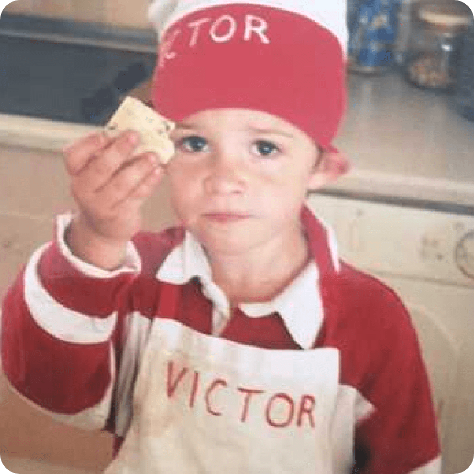 Child in apron and chef hat holding up a square chip